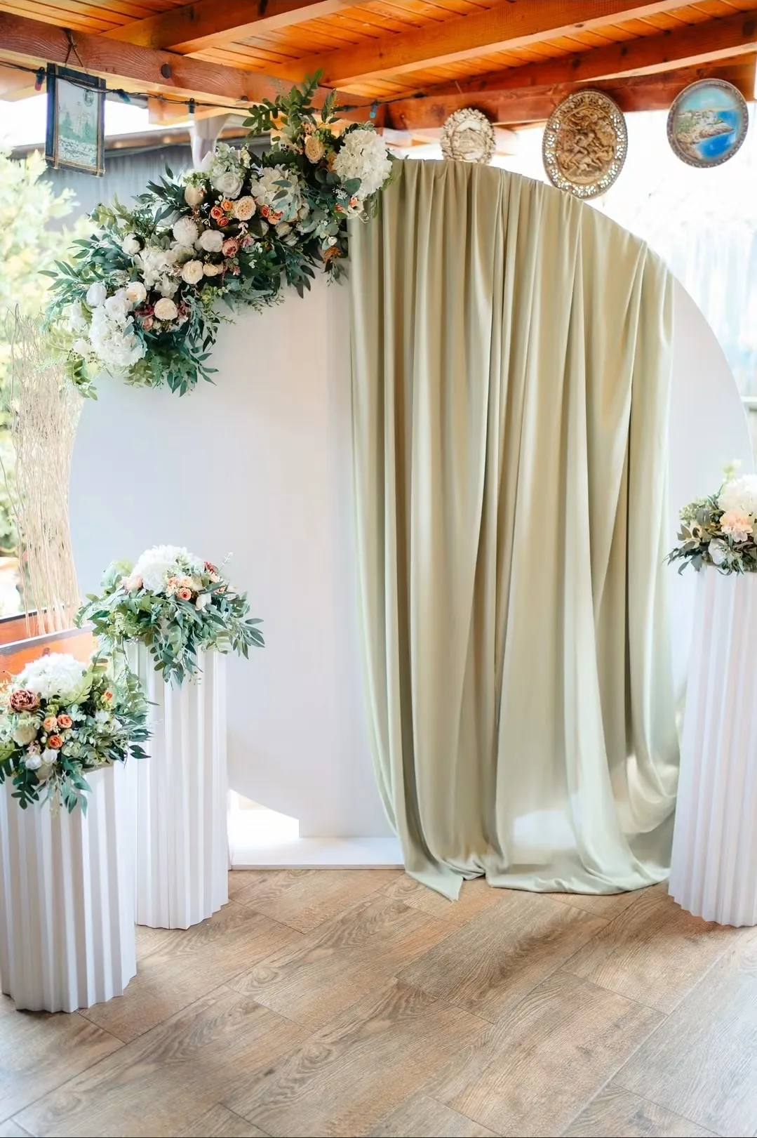 Arcadă foto rotundă cu draperie verde-salvie și aranjamente florale, un stil potrivit și pentru o ceremonie de cununie civilă
